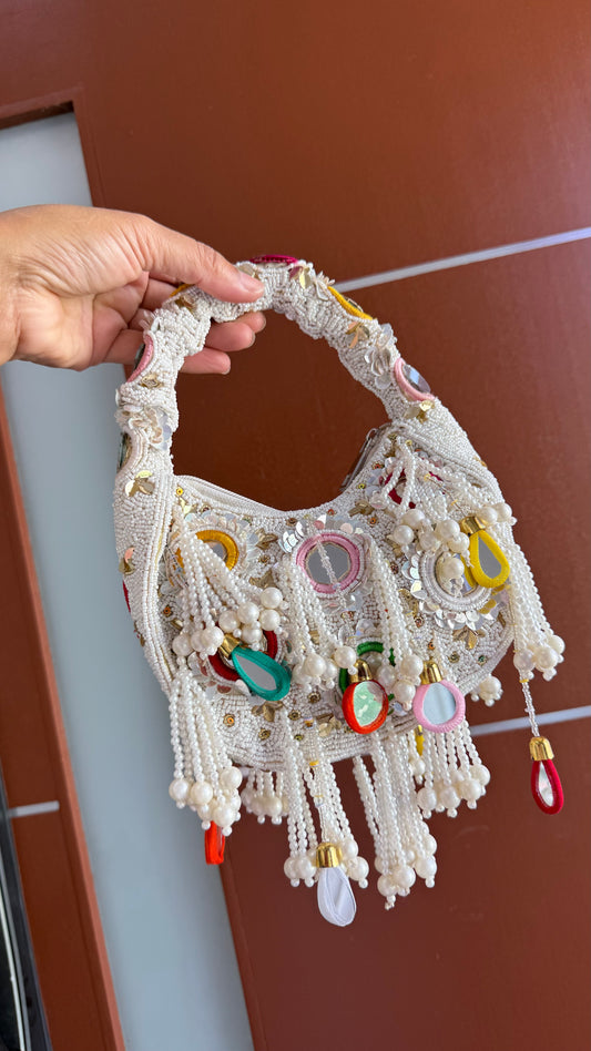 Handmade lace bag with colorful beads and decorations held by a hand against evening bag clutch bag