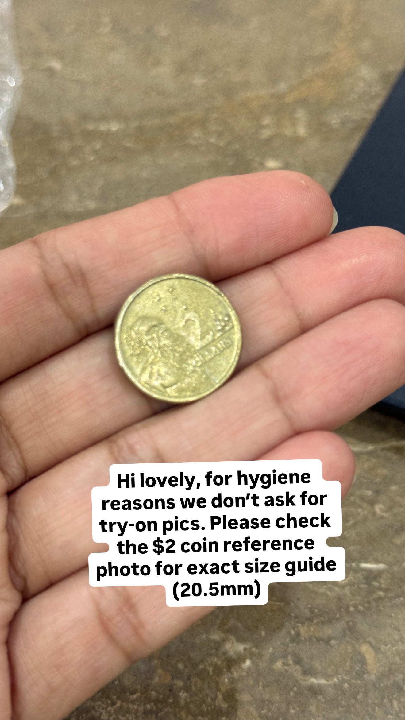 Hand holding a gold coin with text overlay on a concrete surface